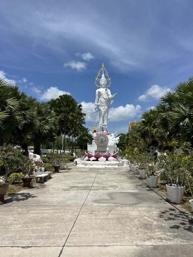 The white standing Buddha and its palm-lined walkway at Na Jomtien